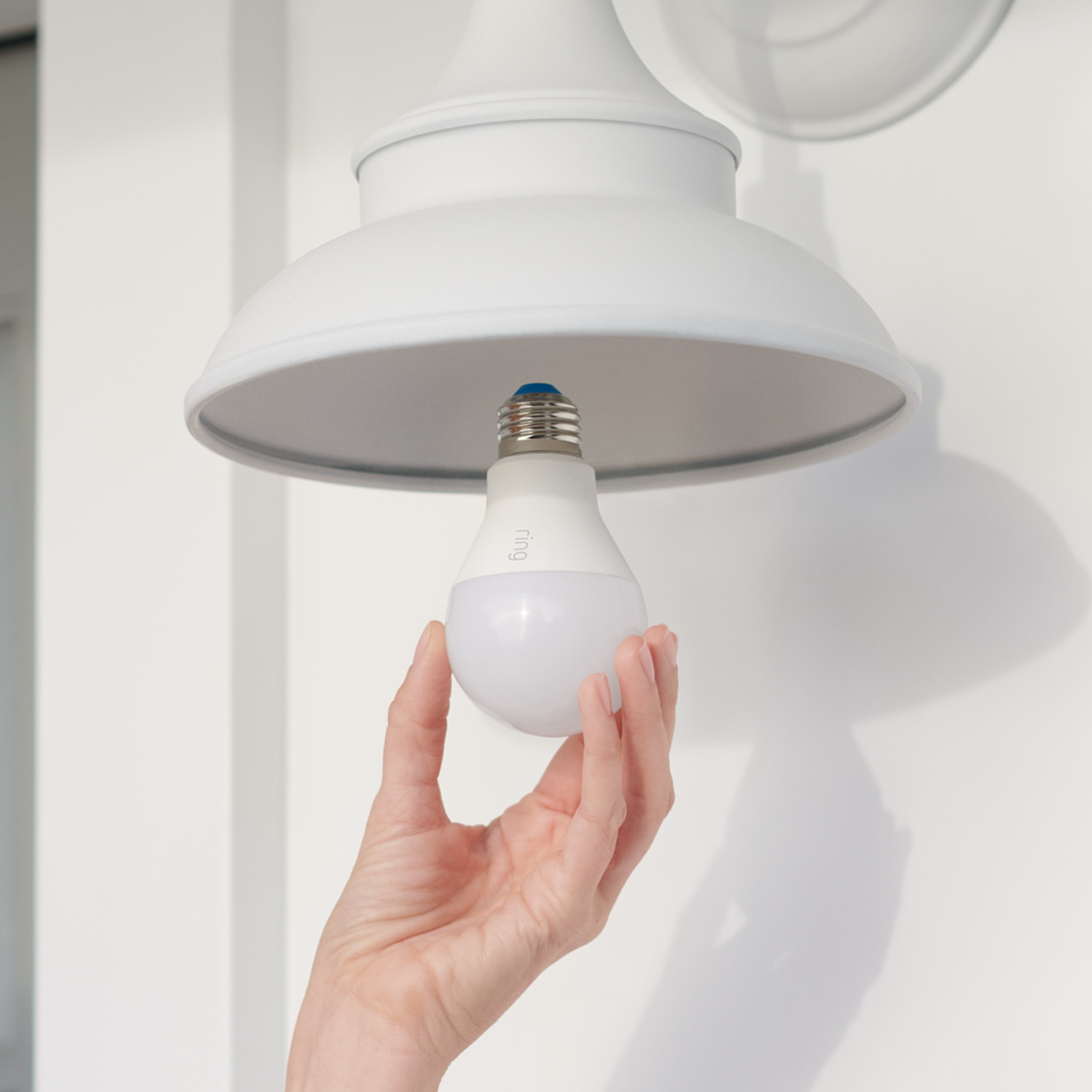 Smart Lighting A19 Smart LED Bulb - Hand installing white A19 Smart LED Bulb into outdoor light fixture, designed for customizable smart lighting.