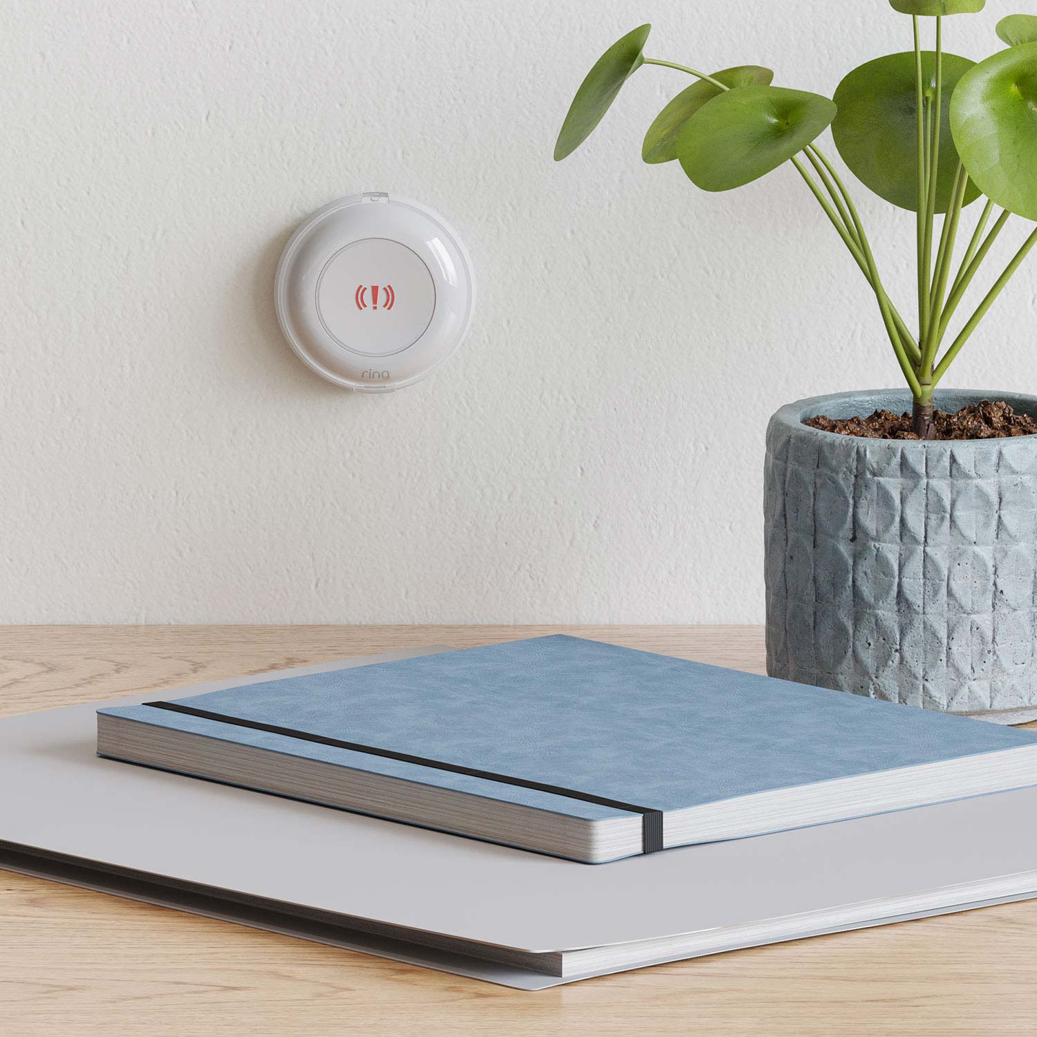 Panic Button (2nd Gen) - White Ring Panic Button 2nd Gen mounted on wall above a desk with books and a potted plant visible.