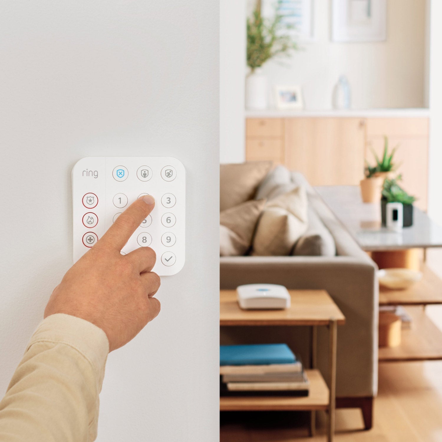 Protected Enhanced Kit (Battery Doorbell Plus + Alarm Security Kit, 8-Piece) - A person presses button on wall-mounted Ring Alarm Keypad, with living room and Ring devices visible in background.