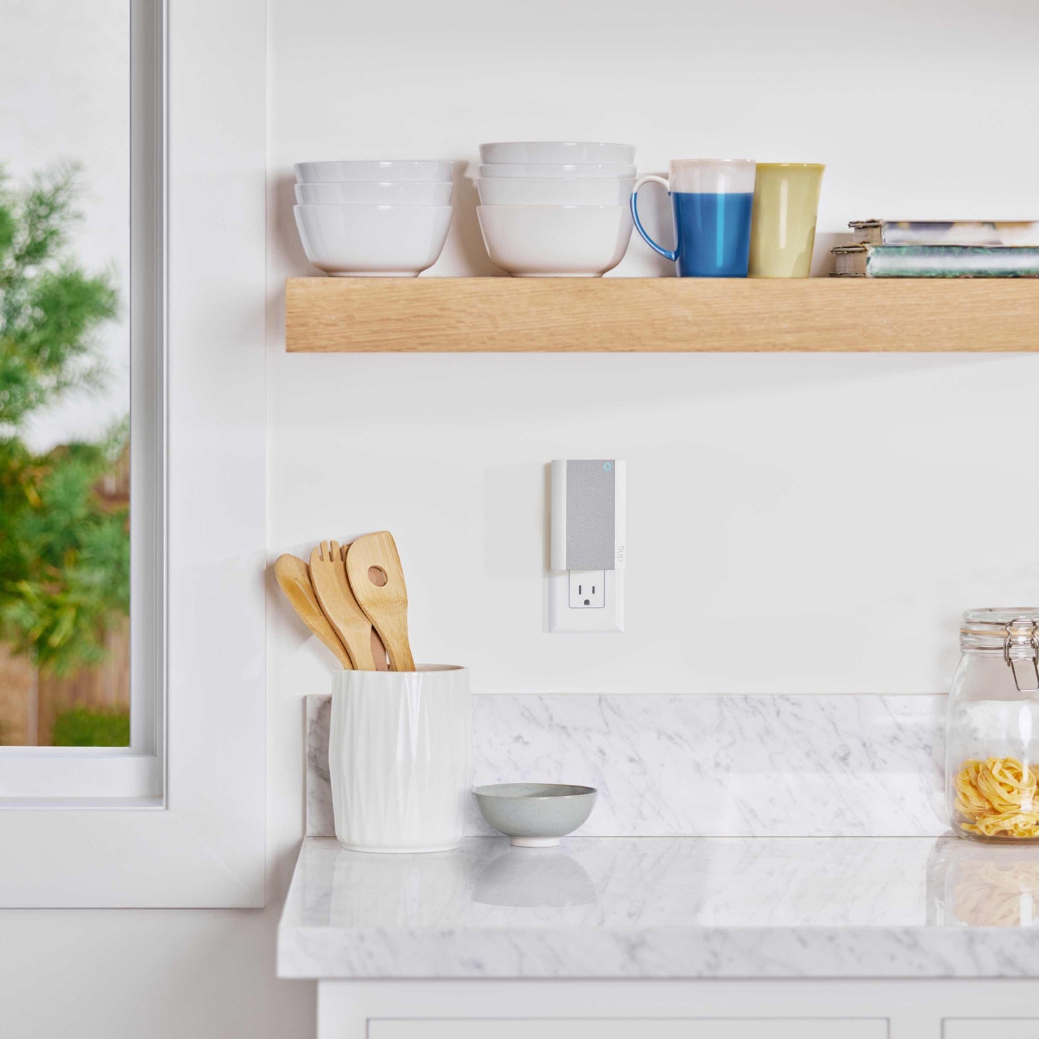 Battery Doorbell Plus with Chime Pro - Ring Chime Pro plugged into a kitchen outlet near white bowls, mugs, wooden utensils, and a marble countertop.