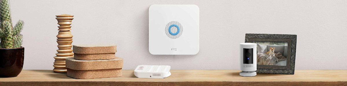 Ring Alarm Base Station, a white Ring security camera, and a Ring Alarm Keypad on a wooden surface