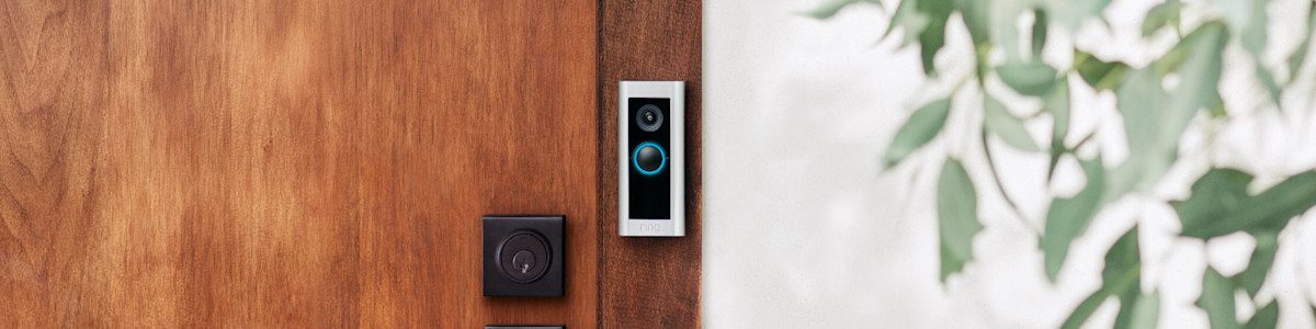 Ring Video Doorbell mounted on wooden door next to black deadbolt lock