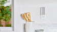 A white and grey Chime Pro mounted on a white wall near wooden kitchen utensils