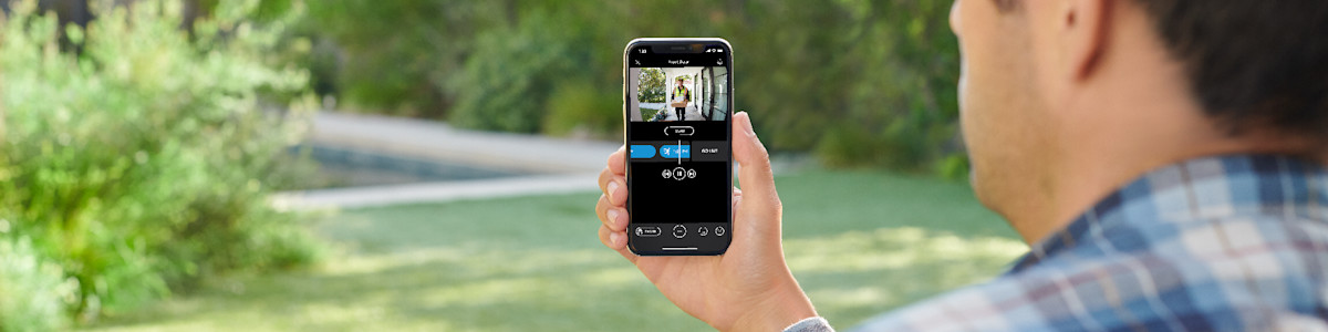 Person viewing security camera feed on smartphone outdoors