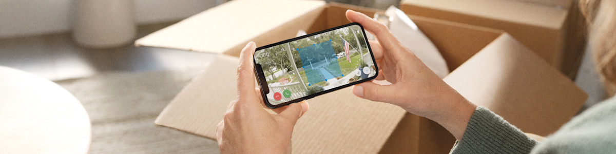 Hands holding a smartphone displaying a back garden scene